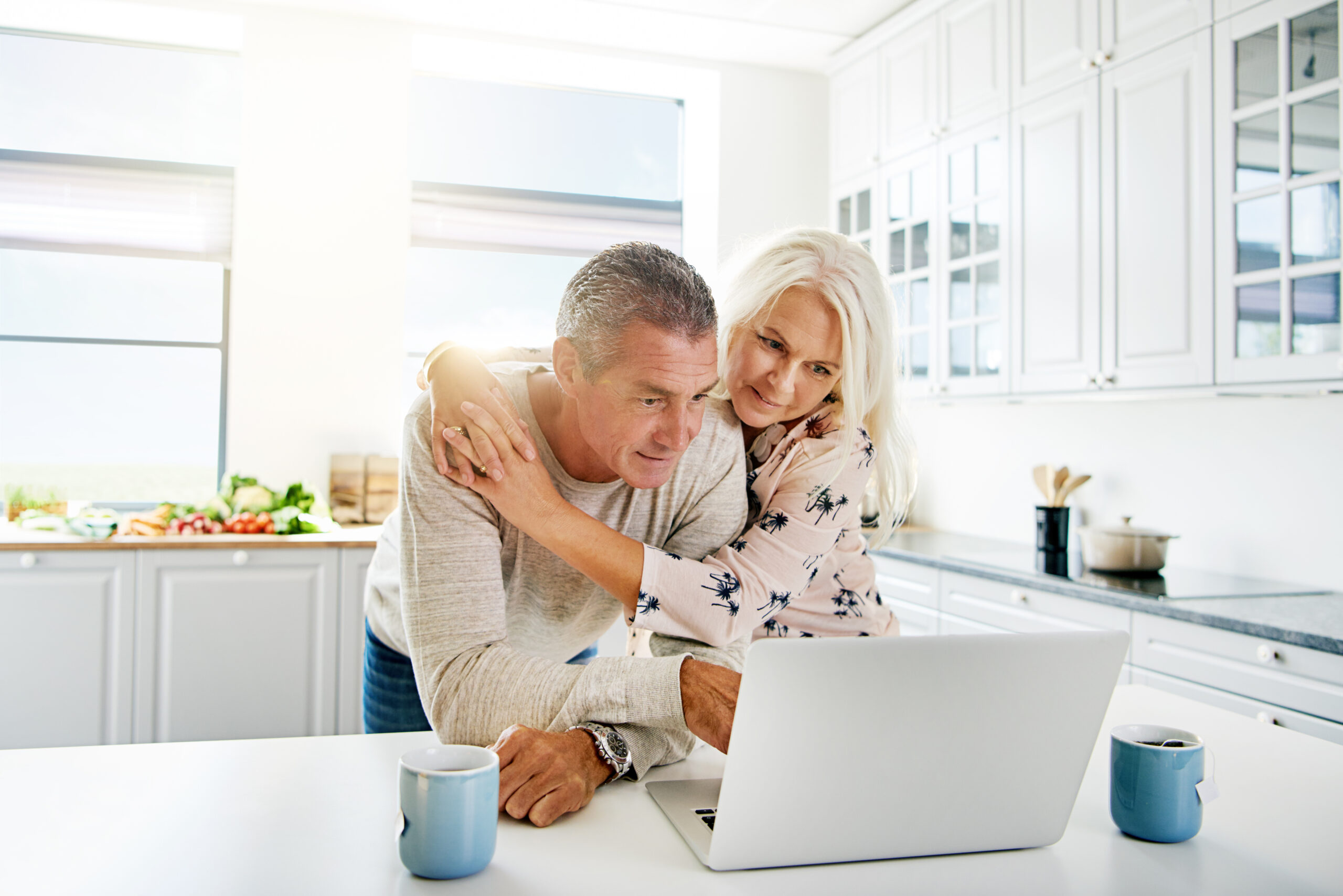 Couple Looking At Laptop In Kitchen